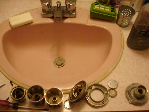 Pink lavatory basin and disassembled pieces of faucet and drain